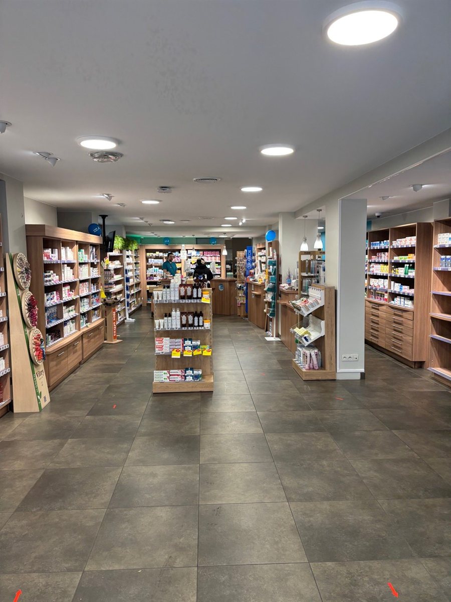 Allée centrale de l'officine avec rayonnages lumineux de chaque côté