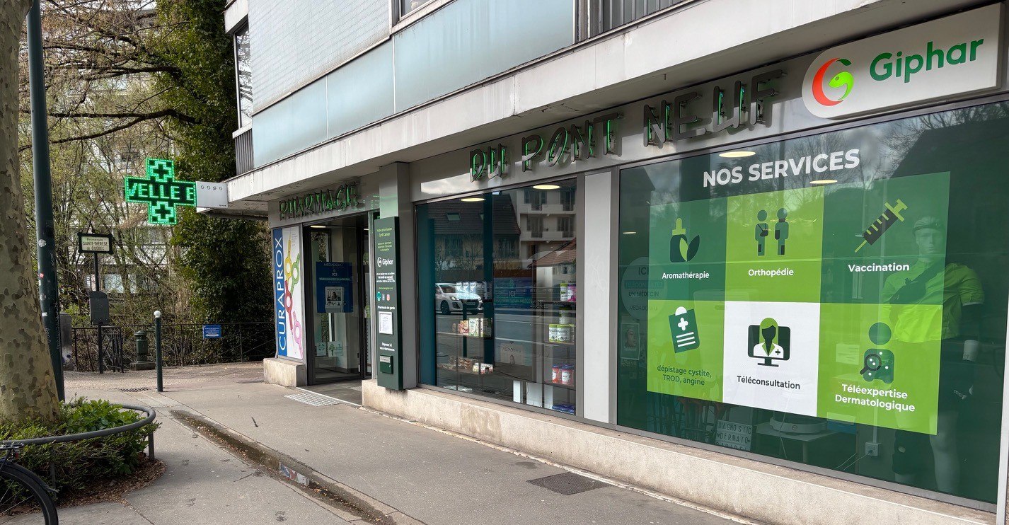 Façade de la Pharmacie du Pont Neuf à Annecy avec sa croix verte et son panneau de services