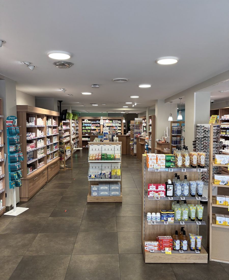 Allée centrale de l'officine, rayonnages en bois clair de part et d'autre