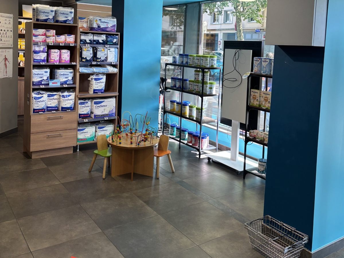 Coin enfants avec petite table de jeux, devant la vitrine et le rayon laits infantiles